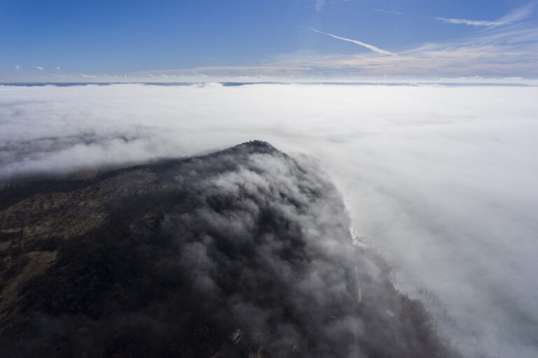 A stunning view of a mountain's peak with clouds around it, captured with a drone.